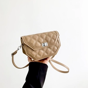 Macro detail of beige quilted crossbody bag with silver clasp and hexagon texture