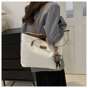 Detail of white plush tote bag showing soft faux fur texture and brown leather strap