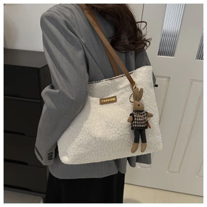 Detail of white plush tote bag featuring faux lamb wool texture and leather strap