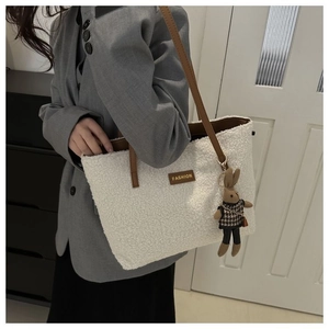 White fuzzy tote bag detail with brown leather strap and a cute bunny plush charm