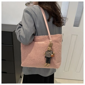 Detail of pink plush tote bag with faux leather straps and bunny doll charm decoration