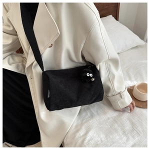Detail view of black corduroy tote bag showing soft ribbed texture and cute fuzzy ball pendant