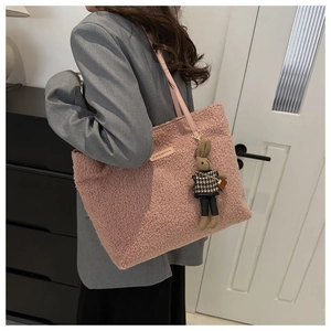 Detail of pink plush tote bag with bunny charm worn on shoulder for daily commute