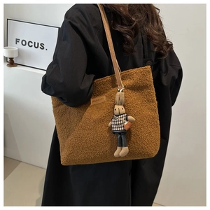 Detail of warm brown plush tote bag with cute rabbit charm and faux leather shoulder strap