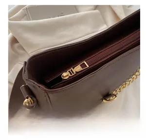 Close-up of smooth gold metal zipper and chain detail on a vintage brown leather bucket bag