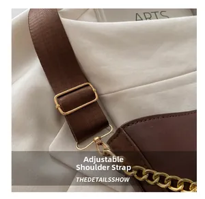 Detail view of adjustable woven strap and polished gold hardware on brown crossbody bag