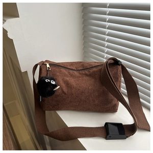 Detail of brown corduroy tote bag showing textured fabric and plush soot sprite charm