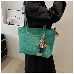 Close-up of green plush tote bag with FASHION leather patch and cute rabbit charm