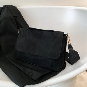 Sac messager minimaliste en daim noir avec détails dorés et bandoulière large tissée