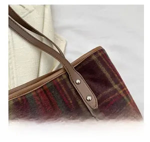 Close-up of vintage plaid tweed tote bag showing leather trim and metal rivet details