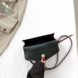 Chic black and brown contrast flap crossbody bag with golden magnetic buckle on beige blazer