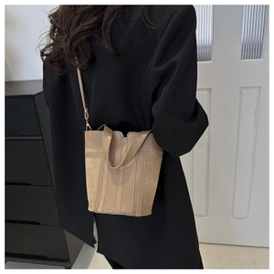 Borsa a secchiello beige in pelle scamosciata e liscia mostrata sulla spalla di un modello