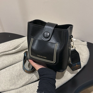 Retro black bucket bag with gold rivets and colorful geometric patterned wide shoulder strap