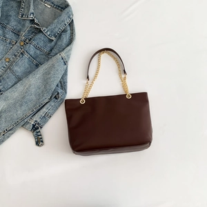 Vintage dark brown chain tote bag with gold hardware on a white fabric background