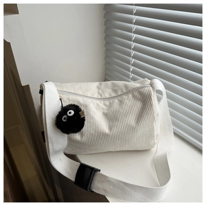 Close-up of cream corduroy tote bag featuring silver zipper and black fuzzy charm