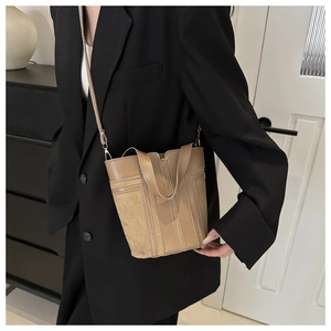 Dettaglio della borsa a secchiello kaki con strisce verticali e texture in pelle