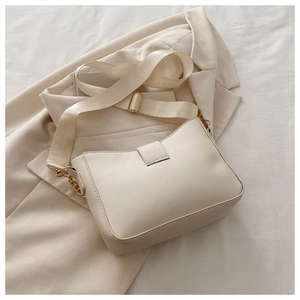Detailed view of beige bucket bag with chain strap on a blazer, elegant texture