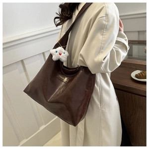 Detail of dark brown tote bag featuring glossy texture and star plush charm
