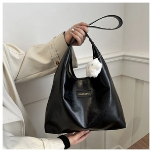 Detail of black glossy PU leather hobo bag with star charm and fashion label
