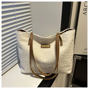 Detail of white plush tote bag with brown leather handles and a fashion label