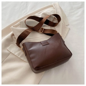 Detail of dark brown bucket bag featuring matte leather and gold adjustable buckle