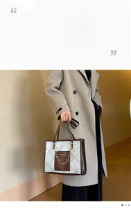 Détail d'un sac cabas bicolore avec tissu matelassé, chaîne en métal et étiquette mode