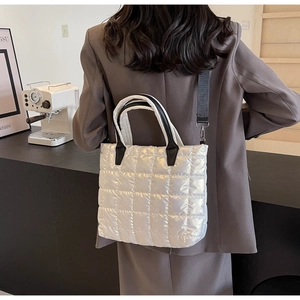 Detailed close-up of a metallic silver quilted tote bag worn by a model in casual blazer