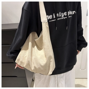 Detail of minimalist off-white oversized faux suede tote bag on model shoulder