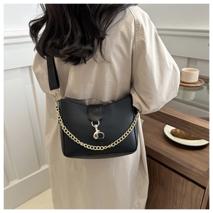 Detail of elegant black bucket bag with a gold metal clasp and a stylish chain strap