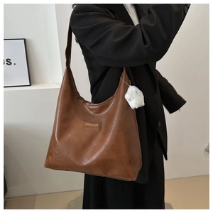 Brown faux leather hobo shoulder bag with plush ball charm and fashion logo detail