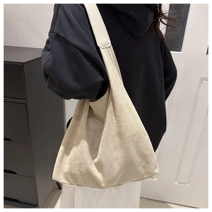 Detail of a large beige suede tote bag worn on shoulder for stylish daily commute