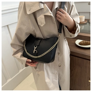 Detail of black matte leather bucket bag with chunky gold chain and metal twist-lock