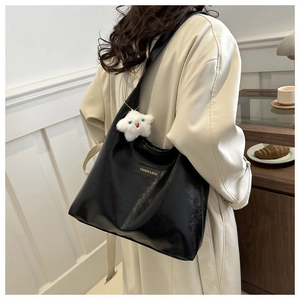 Model wearing a black leather tote bag with a plush star charm and logo detail