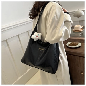 Detail of black glossy PU tote bag with plush star charm and branded fashion label