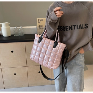 Detail of pink quilted tote bag with black handles and adjustable shoulder strap