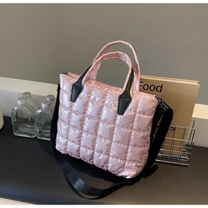 Detail of light pink quilted puffer tote bag with black strap and metallic nylon texture