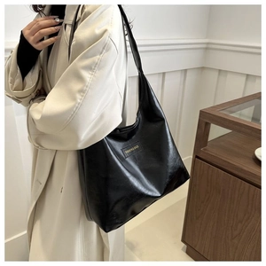 Detail of minimalist black leather tote bag featuring Fashion & Bags logo patch