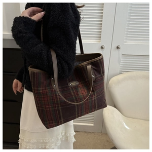 Detail of checkered tote bag with vintage red and green plaid and brown leather handles