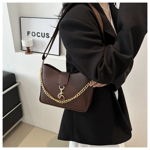 Detailed view of deep brown PU leather bucket bag with gold chain strap and metal clasp