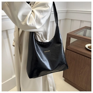 Close-up of black leather tote bag with fashion label shown on a shoulder