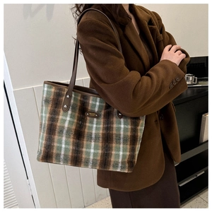 Detail of British style checkered plush tote bag with leather strap and metal logo plate