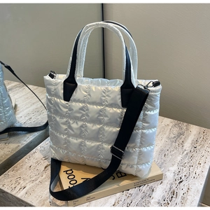 Close-up of quilted silver tote bag with padded texture on a marble surface