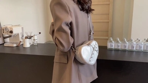 Side view of silver heart-shaped crossbody bag with metal rivets on a female model