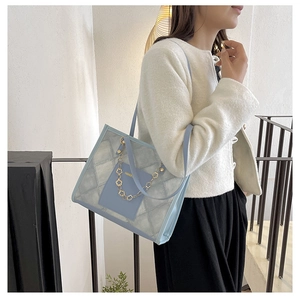 Détail du sac cabas matelassé bleu clair avec chaîne fleurie dorée et étiquette mode