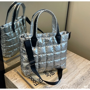 Detail of silver quilted tote bag featuring metallic finish and detachable strap