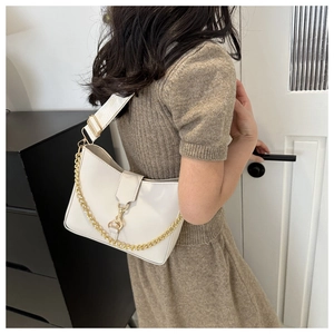 Detailed view of cream bucket bag with gold chain and strap on person in home setting