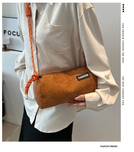 Detail of caramel corduroy cylinder crossbody bag with orange rope strap and fashion patch