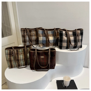 Detail of assorted plaid wool tote bags in various colors on a minimalist display stand
