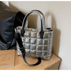 Detail of silver quilted tote bag with metallic finish and adjustable black nylon strap