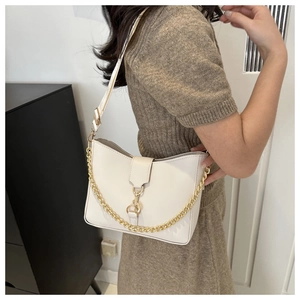 Detailed view of white bucket bag with decorative gold chain on a shoulder strap